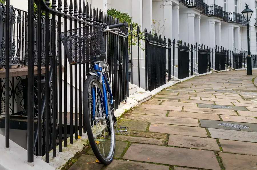 Blue bicycle leaning on black iron railings in front of a row of white rendered townhouses