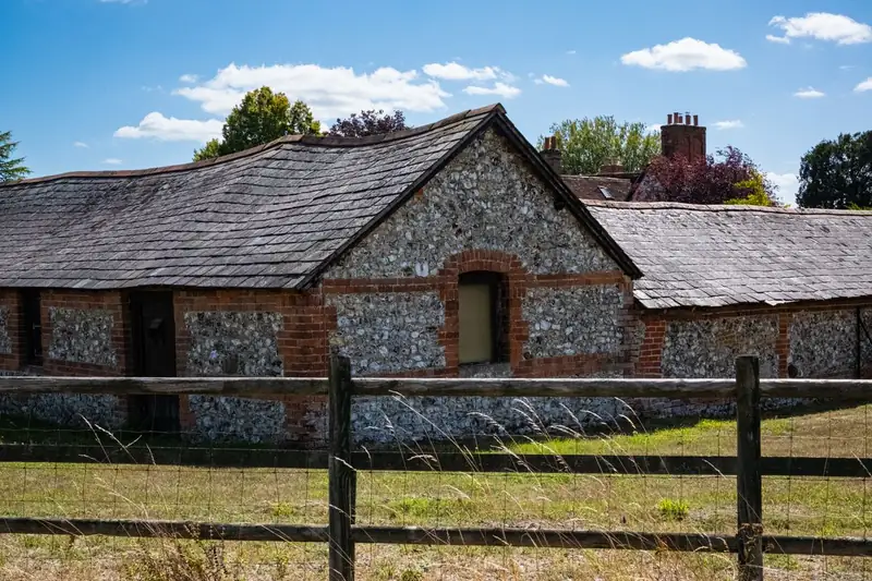 Brick and flint barn behind a post and rail fence, built from the flints that litter the clay-capped chalk around Harpenden