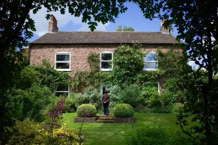Brick farmhouse garden with a raised lawn level held by low brick edging and topiary, a gentle way to terrace a sloping garden in St Albans