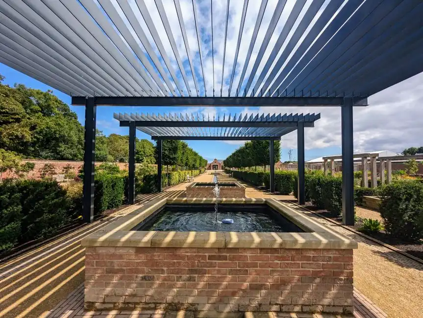 Contemporary dark steel pergola and rill inside an old red brick walled garden in Hertfordshire