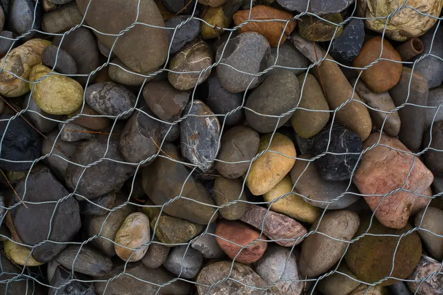 Close-up of a gabion retaining wall basket packed with rounded stone, one retaining wall option for a sloping St Albans garden