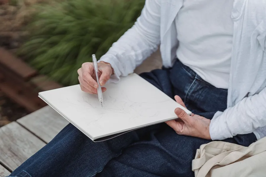 Sketching notes on a pad beside a planted border while taking a garden design brief in St Albans
