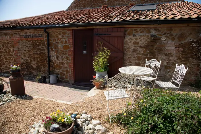 Flint and brick courtyard with gravel, pots and a small bistro set, the scale of garden where a consultation may be enough