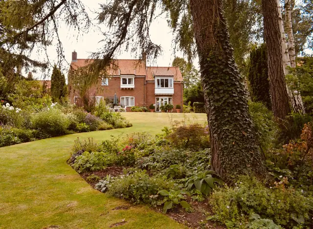 Red-brick Hertfordshire house with lawn and mixed borders, a typical St Albans garden design project