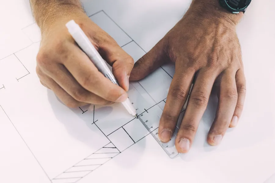 Hands drawing a scaled layout with a metric scale rule, the masterplan stage of a garden design in St Albans