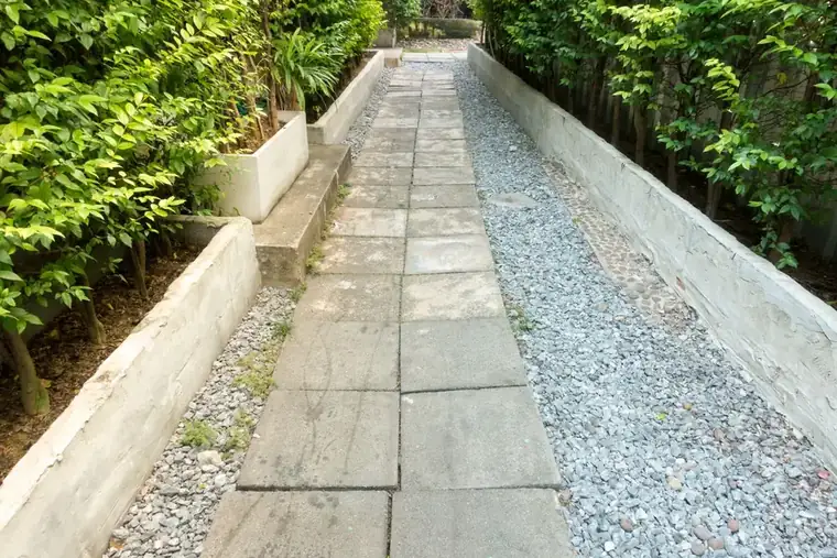 Paved garden path between concrete raised planters with gravel drainage strips, the structural work that adds cost to a sloping garden