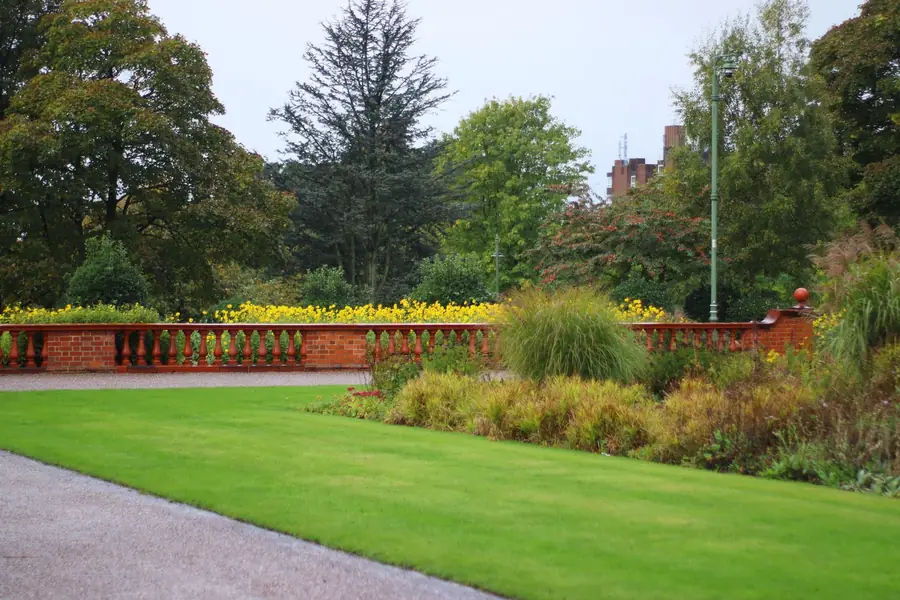 Fine bound gravel path curving along a lawn below a red-brick balustrade and grass border, a low-cost permeable surface for larger Harpenden and St Albans plots
