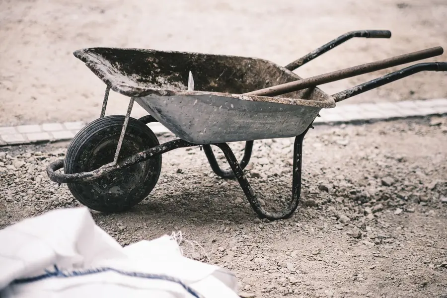 Wheelbarrow and tools on a part-built garden site between phases in Hertfordshire