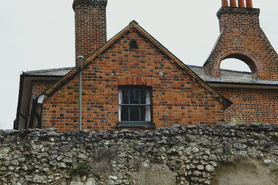 Weathered flint and chalk rubble garden wall in front of a red brick period building in St Albans