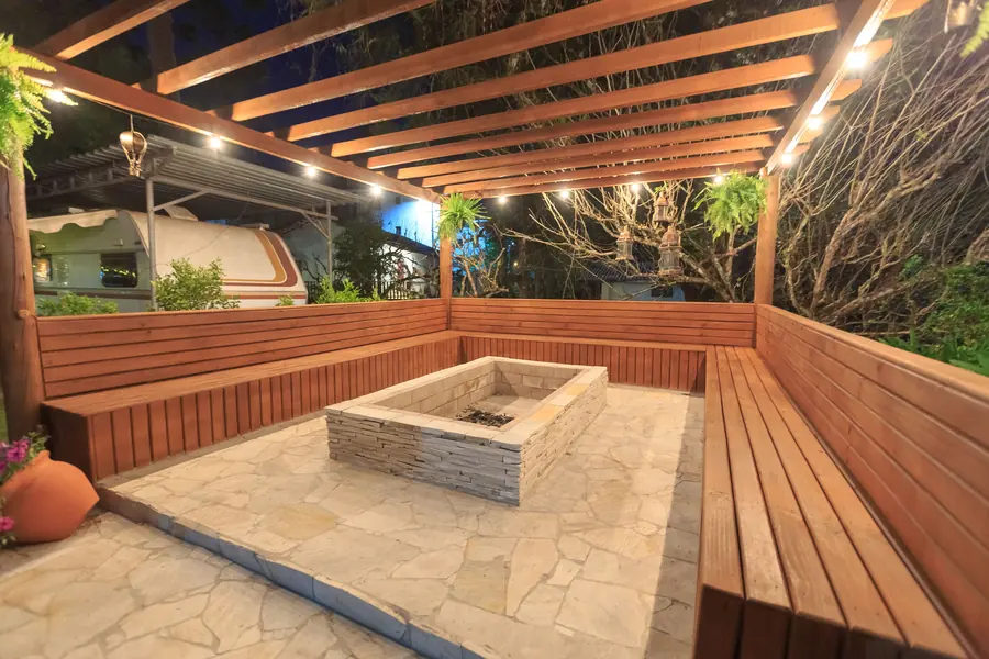 Timber pergola with built-in bench seating around a sunken fire pit