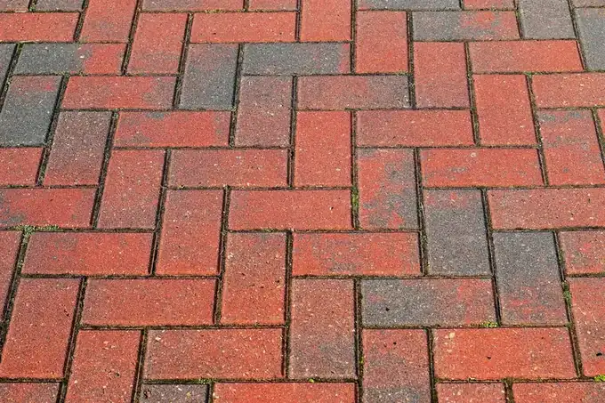 Red and grey clay brick pavers laid in a herringbone pattern, close up