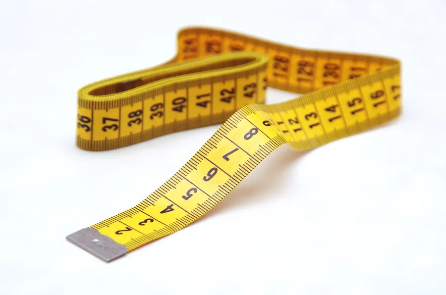 Yellow tape measure curled on a white surface