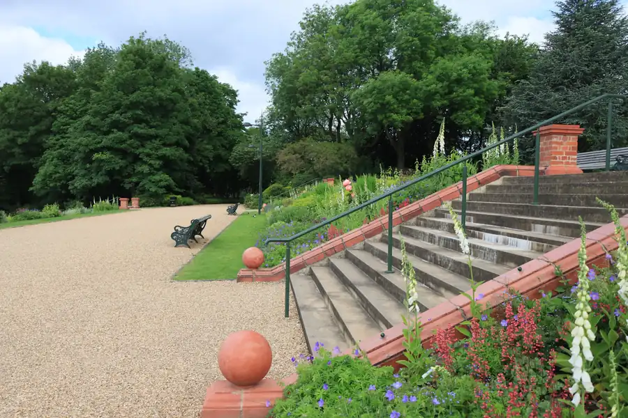 Landscaped garden steps with metal railings rising between planted borders